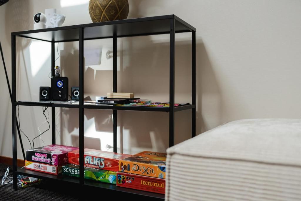 A black metal shelf unit with various board games and a camera on top.