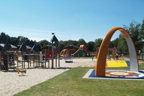 A playground with various play structures, a sandy area, and a large inflatable arch. - Gemütliches Ferienhaus für 2-6 Personen mit privater Hottub in schönen Lochem (Lochem)