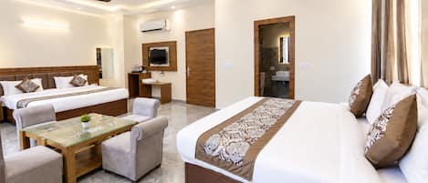 A hotel room with a large bed, a smaller bed, a sofa, a glass-top table, and a TV.