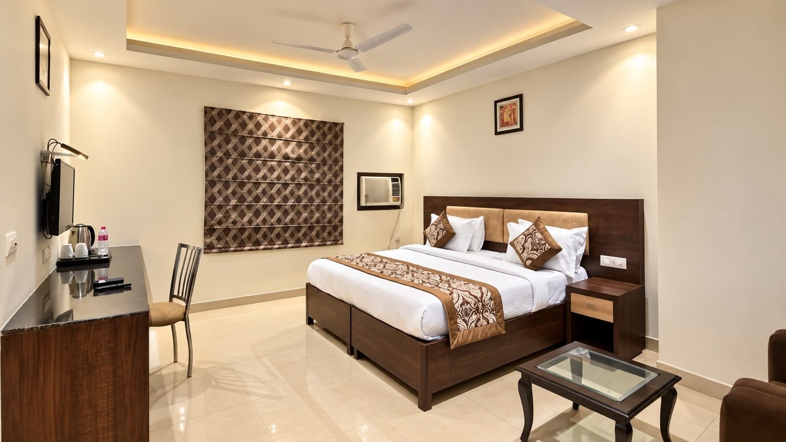 A modern hotel room with a bed, bedside table, chair, desk, and a ceiling fan.