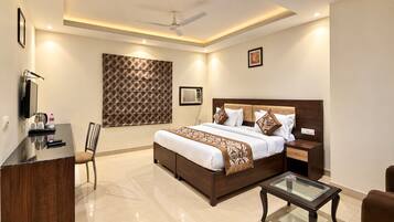 A modern hotel room with a bed, bedside table, chair, desk, and a ceiling fan.