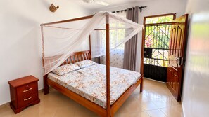 Ein Schlafzimmer mit Himmelbett, einem Holznachttisch und Blick durch ein Fenster mit einem Metallgitter.
