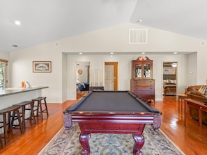 A pool table in a room with a bar and stools, a wooden cabinet, and a billiards rack. - 2 houses sit on 1350ft Peninsula-Sleeps 18-Waterslide. Green light. Fish Feeder. (Dadeville)