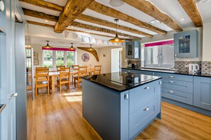 A modern kitchen with a central island, wooden dining table, and chairs. - Host Stay - Yeoman s House (Canterbury)