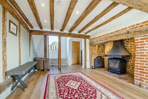 A spacious room with exposed wooden beams, a brick fireplace, and a bench. - Host Stay - Yeoman s House (Canterbury)