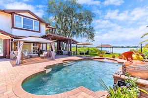 Ein Swimmingpool mit Whirlpool, Gartenmöbeln und einer überdachten Terrasse.