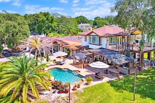 Ein Wohnhaus mit Schwimmbad, Sitzgelegenheiten im Freien und einer überdachten Terrasse.