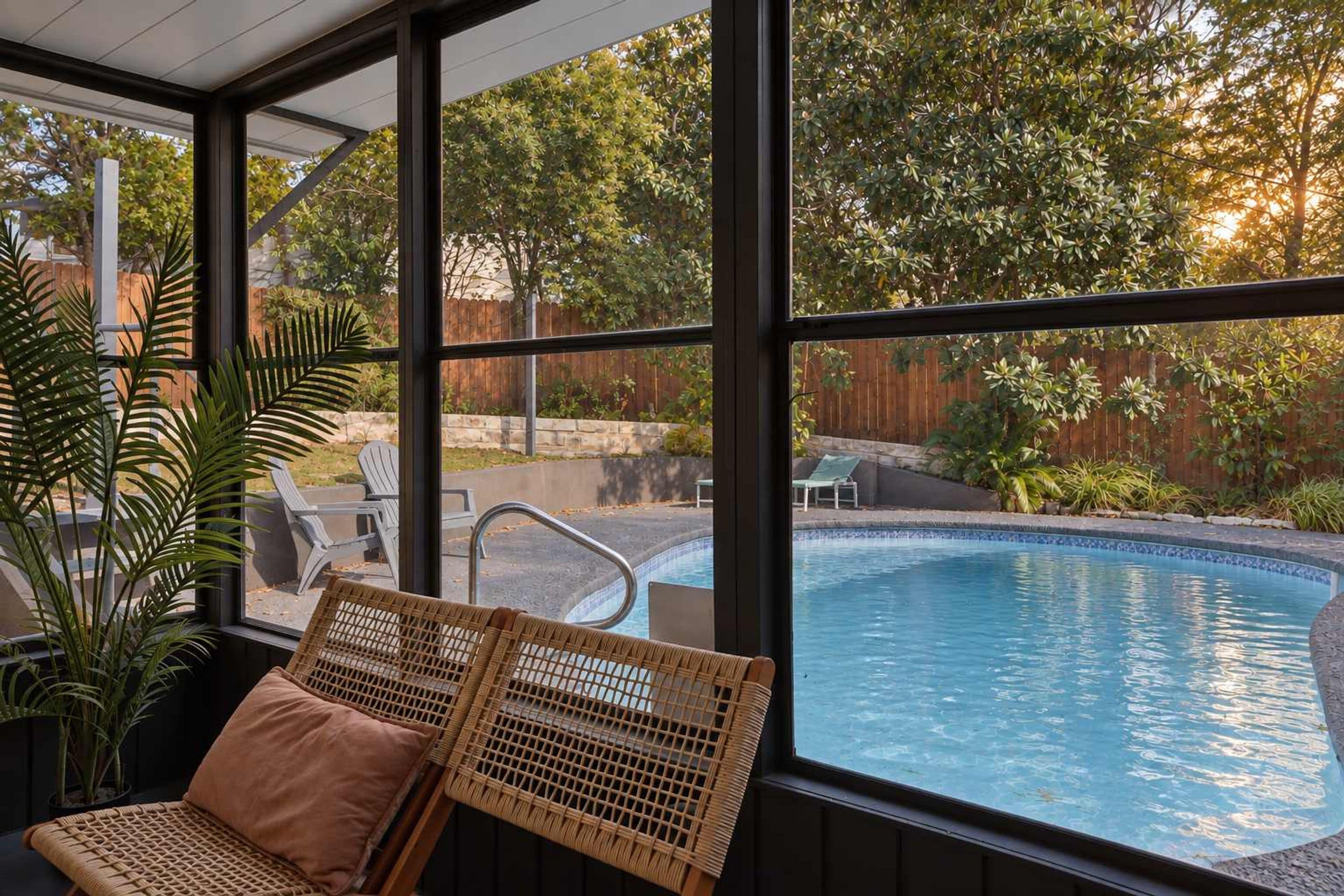 A poolside area with wicker chairs and a view of a swimming pool.