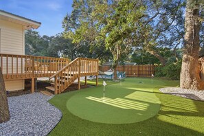 Ein Garten mit Holzterrasse, Kunstrasen und einem kleinen Putting-Green.