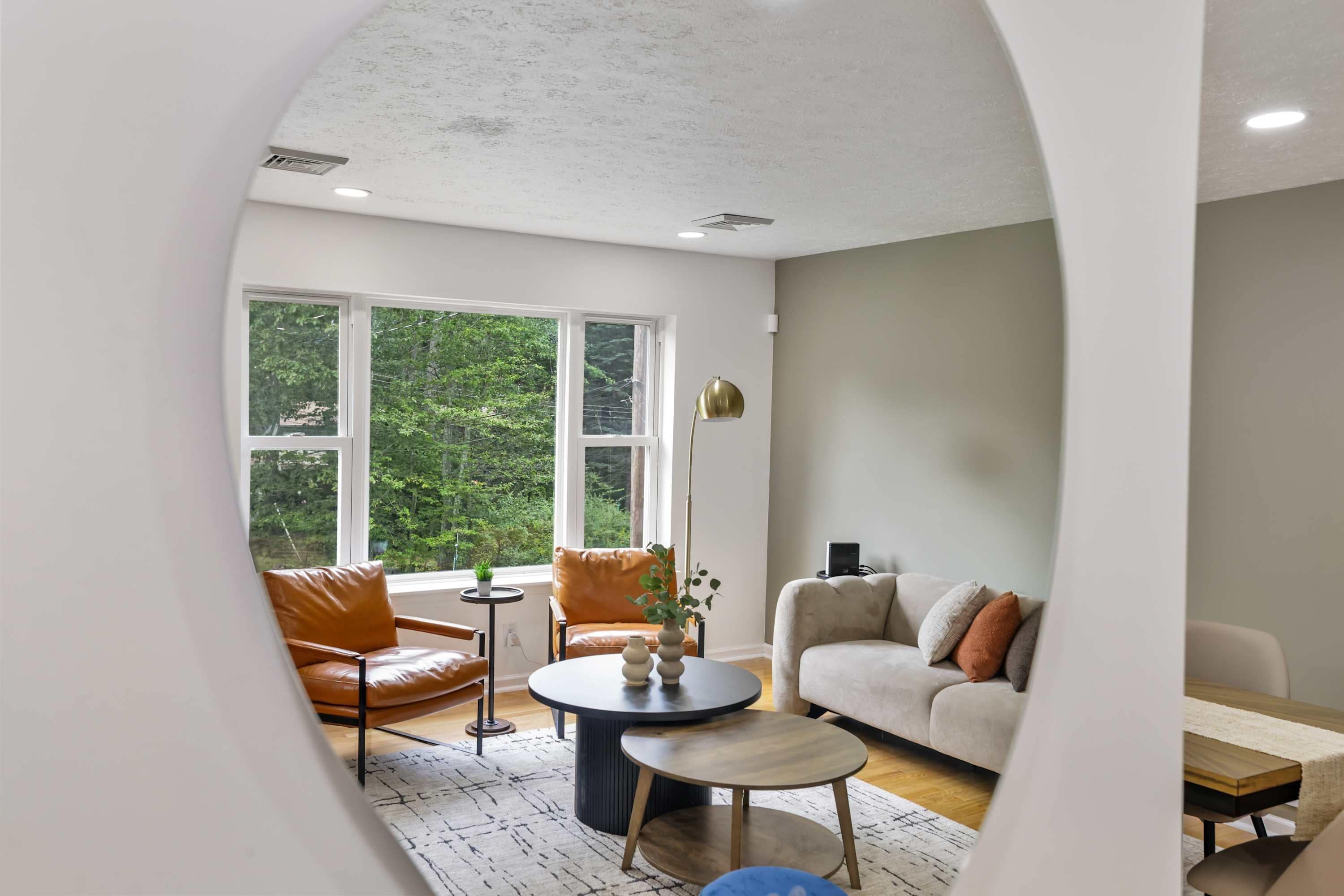 A modern living room with a sofa, armchairs, a coffee table, and a lamp.