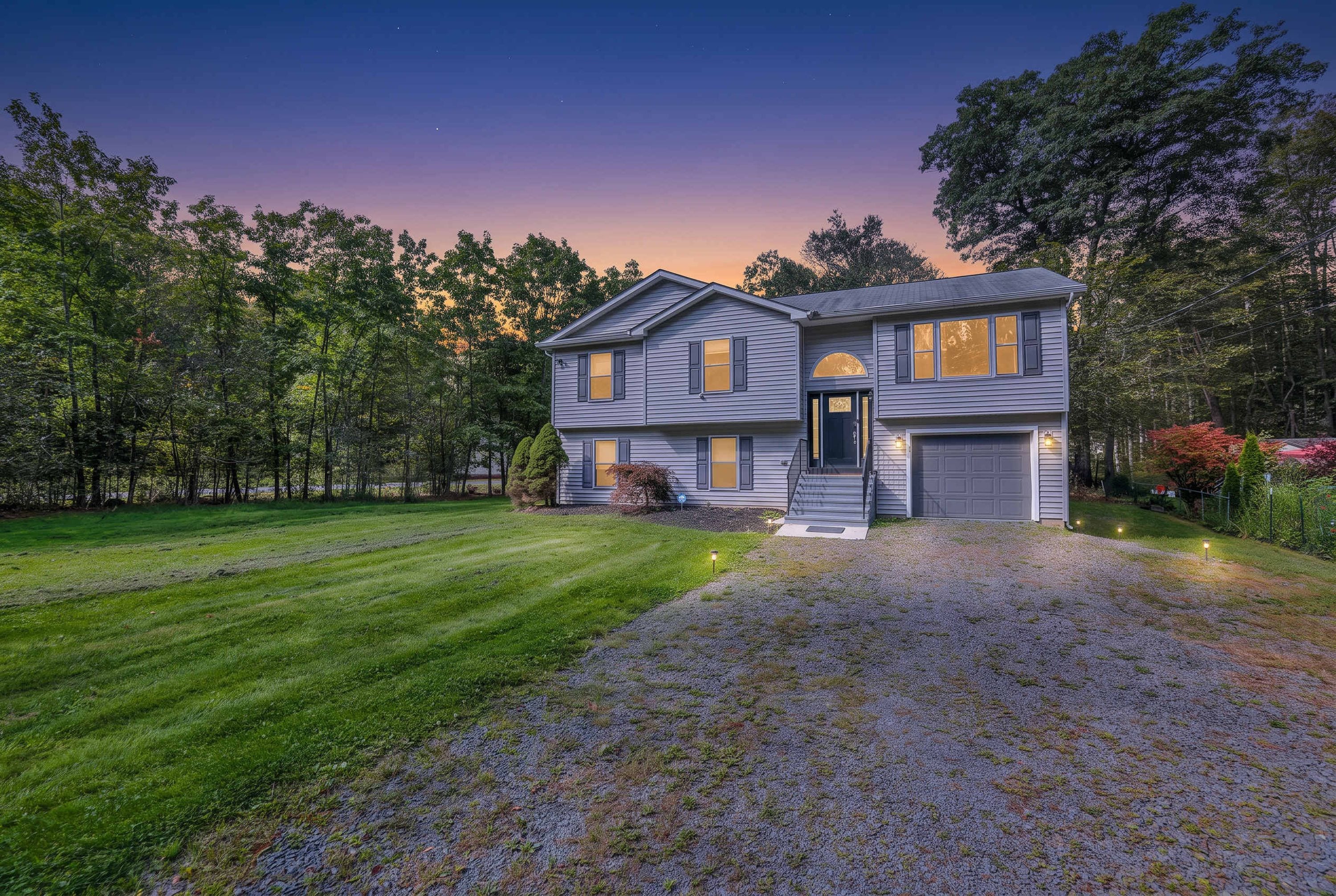A two-story house with a front porch, a driveway, and a well-maintained lawn.