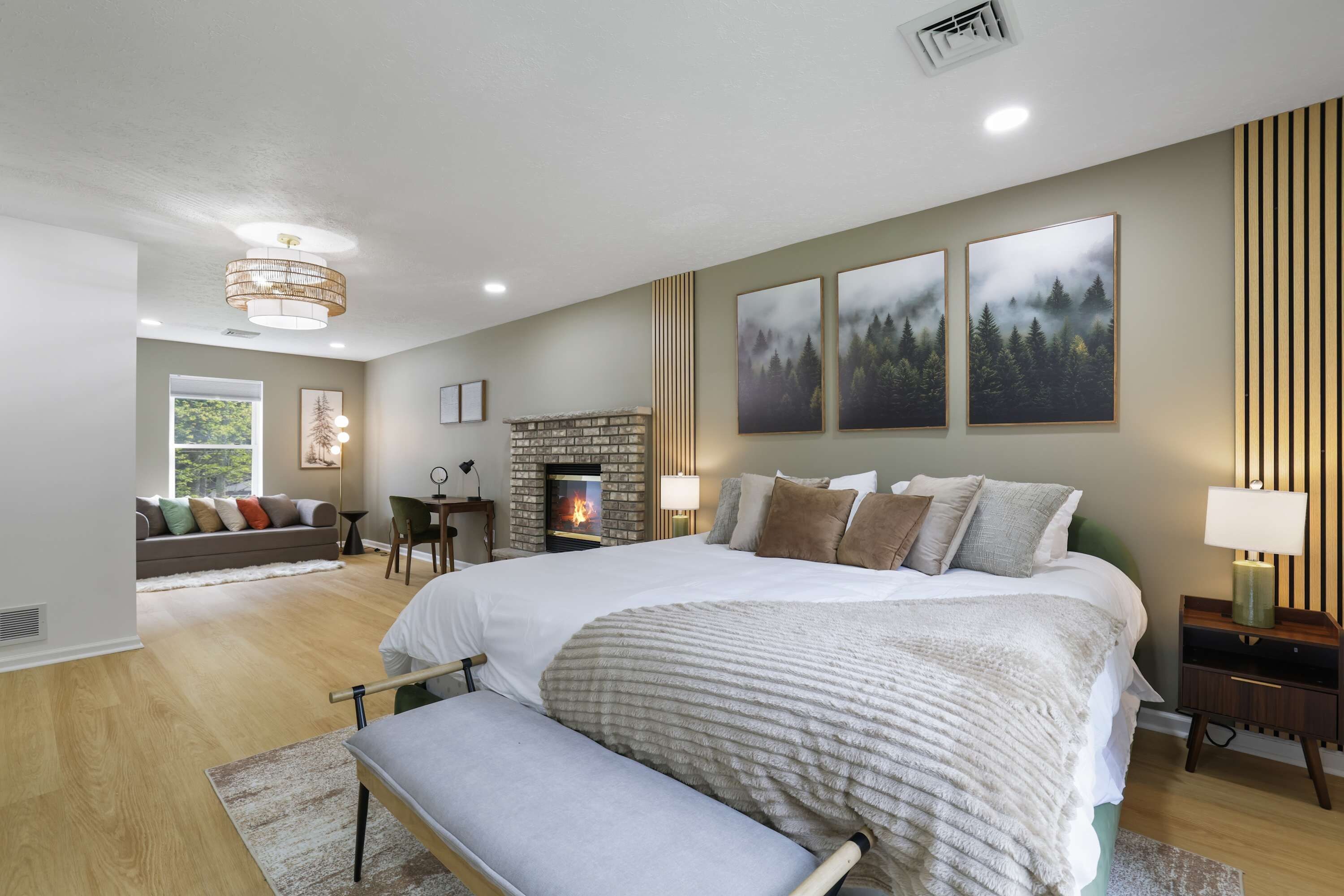 A modern bedroom with a large bed, a fireplace, and artwork on the wall.