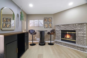 A modern living room with a fireplace, a dining table, and bar stools. - Your Poconos Escape Game Room Firepit Grill (Tobyhanna)