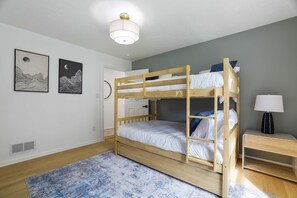 A bunk bed room with a ceiling light, a framed artwork on the wall, and a bedside table with a lamp. - Your Poconos Escape Game Room Firepit Grill (Tobyhanna)