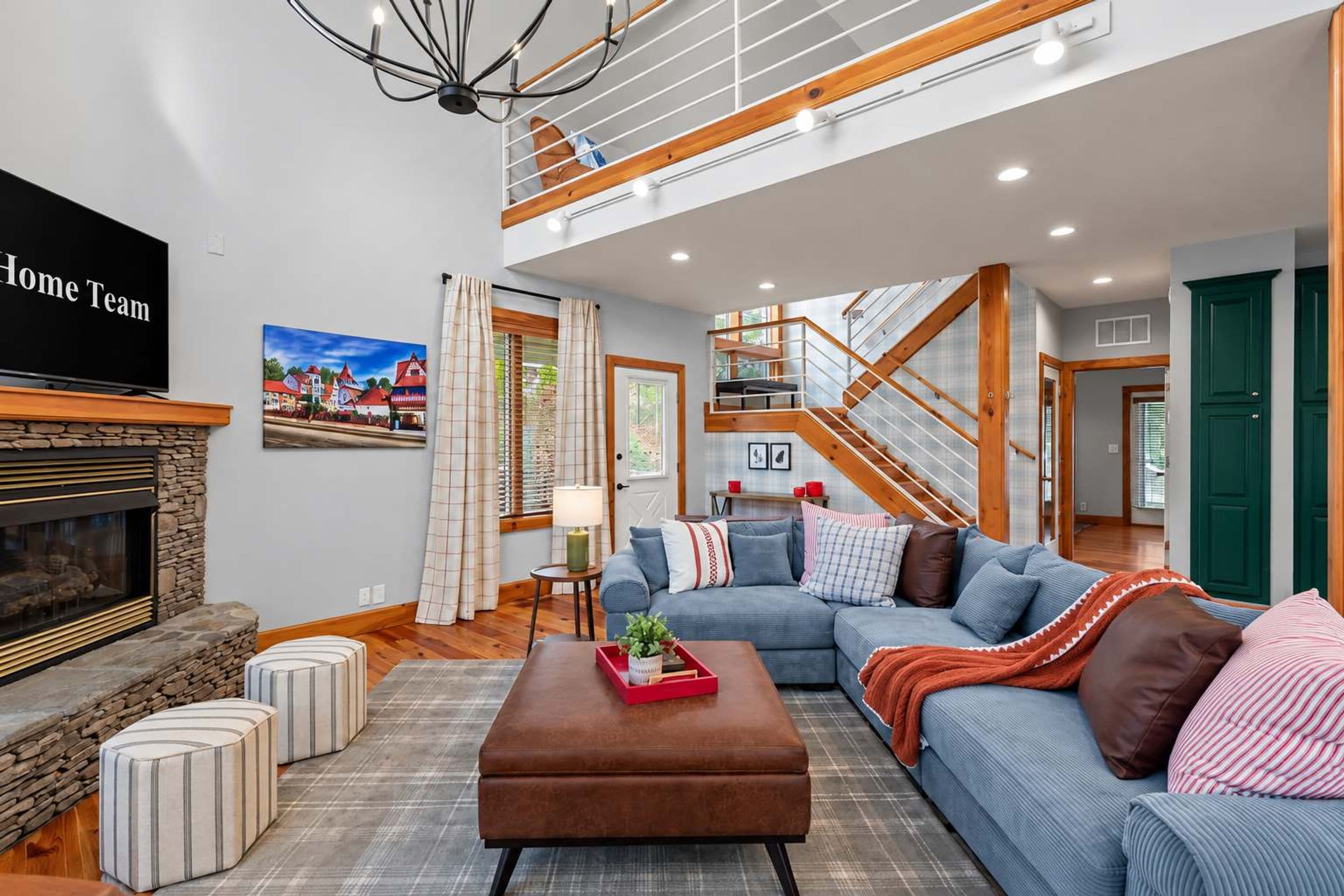 A spacious living room with a fireplace, a large sofa, a coffee table, and a staircase leading to an upper level.