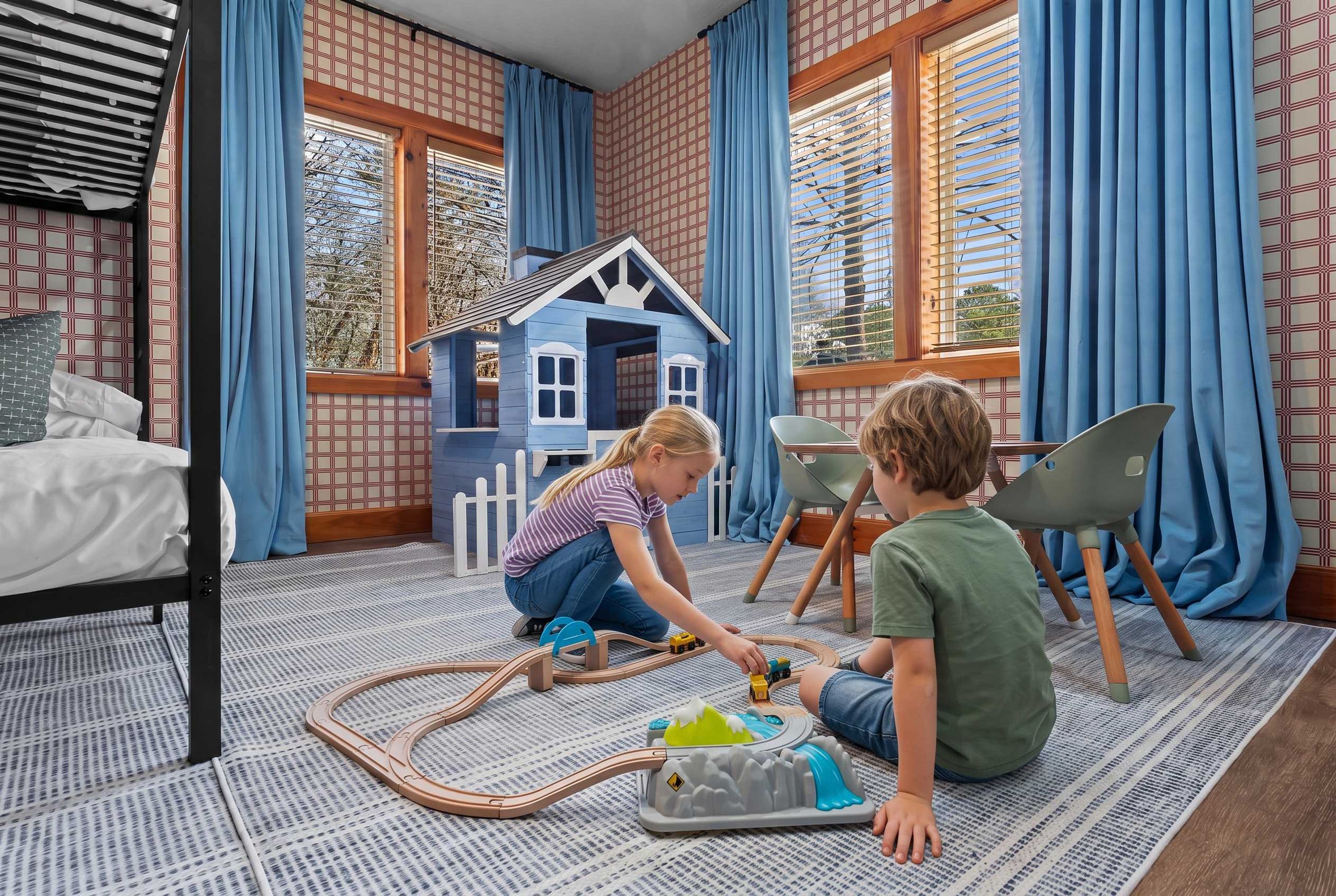 A room with a bed, a play area with toys, and a window with curtains.