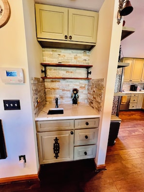 Una cocina con protector de piedra, armarios de madera y horno empotrado.