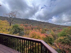 A view from a wooden deck overlooking a forested hillside with autumn foliage. - Mountainview Manor with VIEWS GALORE in Beech Mountain close to the ski slopes (Beech Mountain)