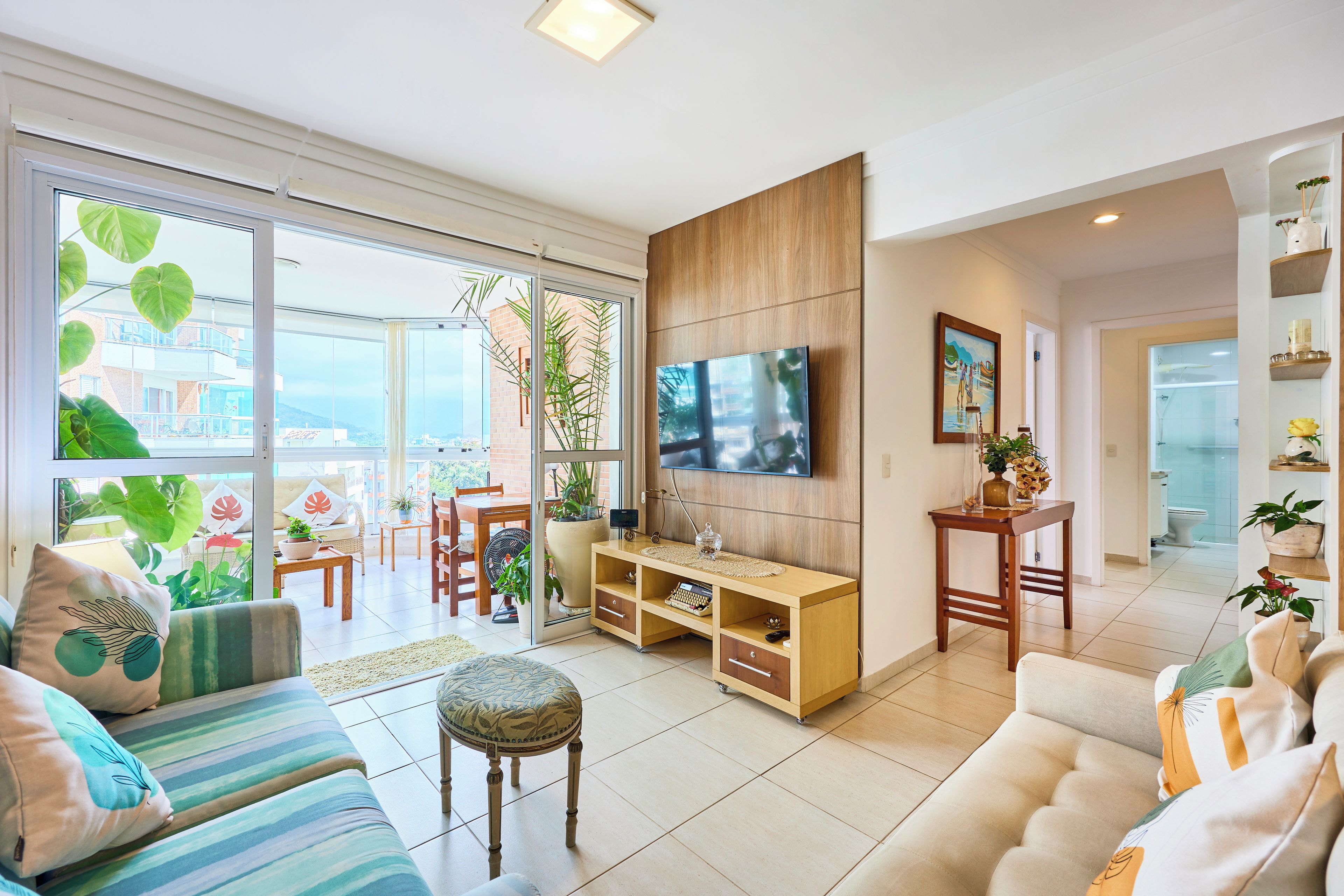 A spacious living room with a large TV, comfortable seating, and a view of the outdoors.