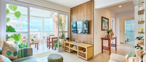 A spacious living room with a large TV, comfortable seating, and a view of the outdoors.
