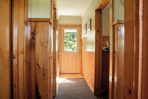 A wooden hallway with a door leading to a garden. - Original Camp Bungalow; 12 Acres; Trampoline (Roscoe)