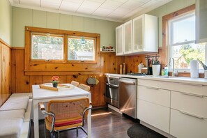 A kitchen with wooden cabinets, a stainless steel dishwasher, and a window with a view of the outside. - Original Camp Bungalow; 12 Acres; Trampoline (Roscoe)
