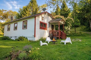 A white house with a porch and a fire pit in the yard.