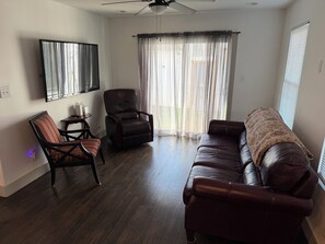 A living room with a leather sofa, a recliner, a striped armchair, a small table, and a ceiling fan. - The Fort Worth Overlook (Fort Worth)