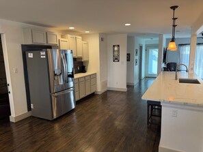 A modern kitchen with a stainless steel refrigerator, white cabinets, and a marble countertop. - The Fort Worth Overlook (Fort Worth)