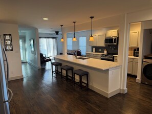 A modern kitchen with a central island, bar stools, and pendant lighting. - The Fort Worth Overlook (Fort Worth)