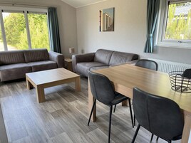 A modern living room with a sofa, a coffee table, and a dining table with chairs.