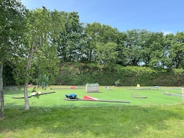 En park med en grön gräsmatta, träd och olika typer av lekredskap.