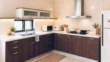 Une cuisine moderne avec des meubles de couleur bois foncé, une hotte en acier inoxydable, un four à micro-ondes et un réfrigérateur.