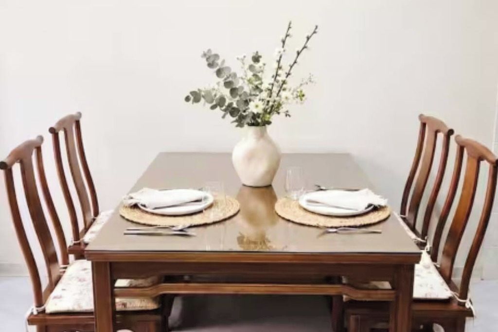 Une table à manger avec quatre chaises, un vase de fleurs et un set de table.