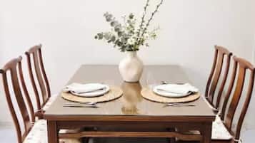 Une table à manger avec quatre chaises, un vase de fleurs et un set de table.