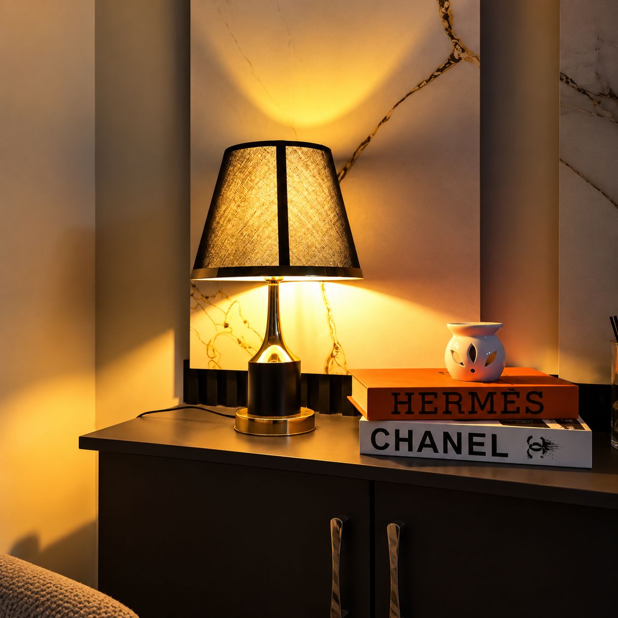 Ein Nachttisch mit einer Lampe, einem Buch mit dem Titel 'HERMES' und einer dekorativen Vase.