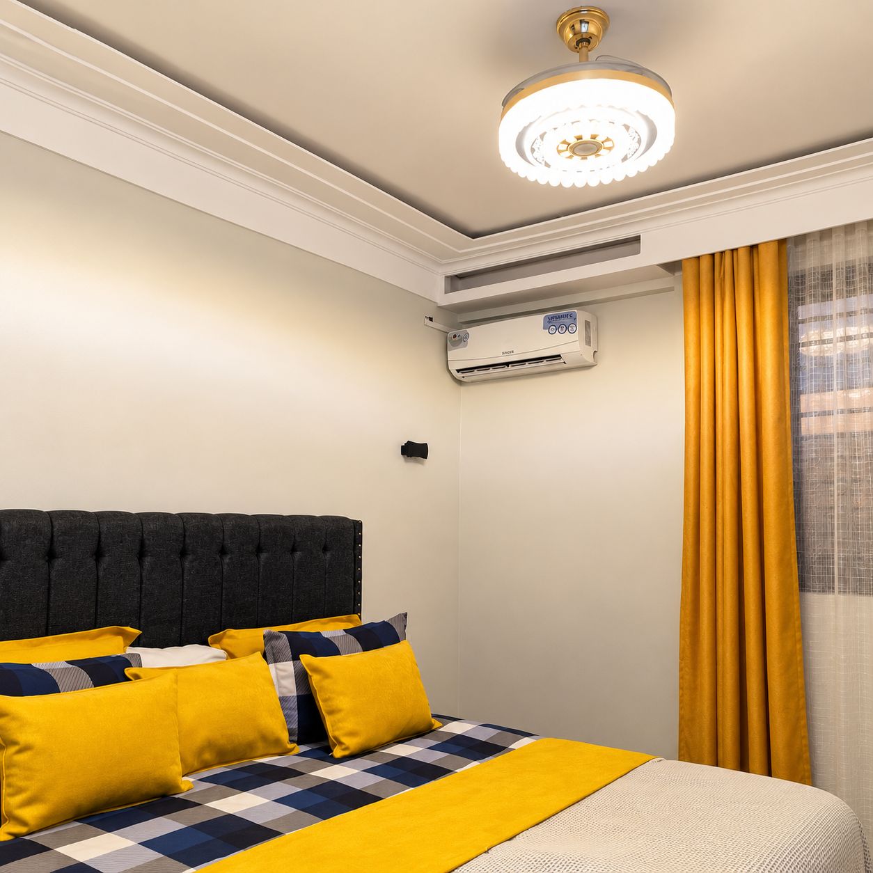 Ein Hotelzimmer mit Bett, Deckenventilator, Klimaanlage und einem Fenster mit Vorhängen.