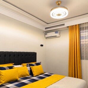 Ein Hotelzimmer mit Bett, Deckenventilator, Klimaanlage und einem Fenster mit Vorhängen.