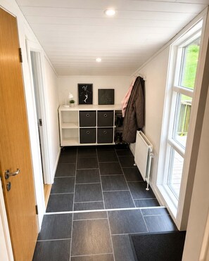 A room with a white door, a radiator, a window, and a storage unit with black drawers.