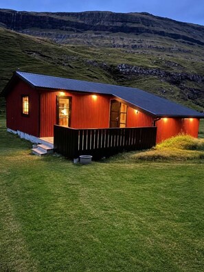A red wooden house with a porch, a door, and a window. - Saksun Mountain & Beach Cottage (Saksun)