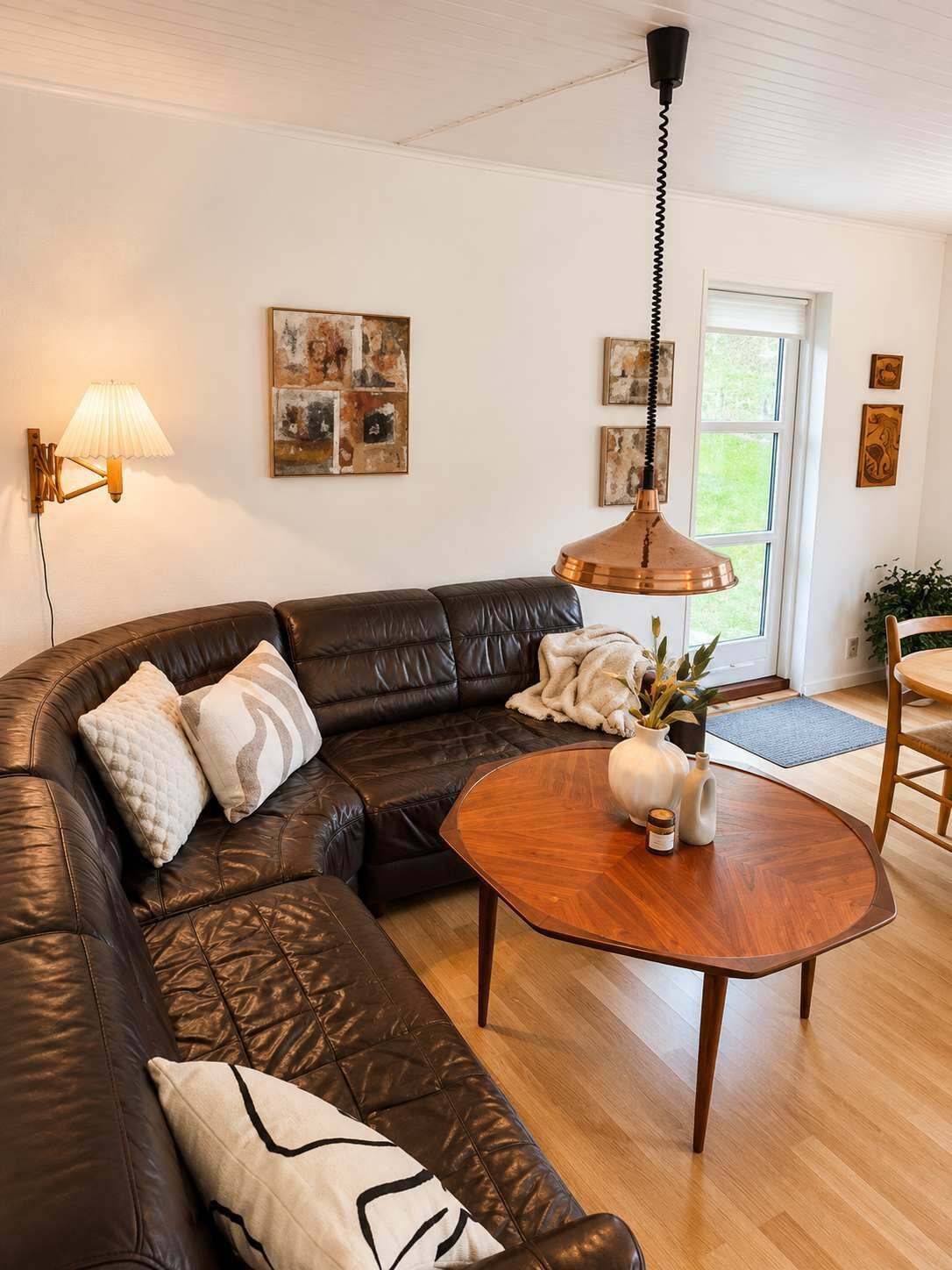 A living room with a leather sectional sofa, a round wooden coffee table, and a pendant light.