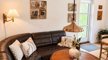 A living room with a leather sectional sofa, a round wooden coffee table, and a pendant light.