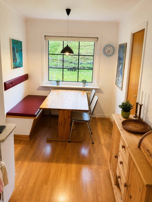 A compact kitchen with a built-in bench seating area, a window with a view, and a clock on the wall.