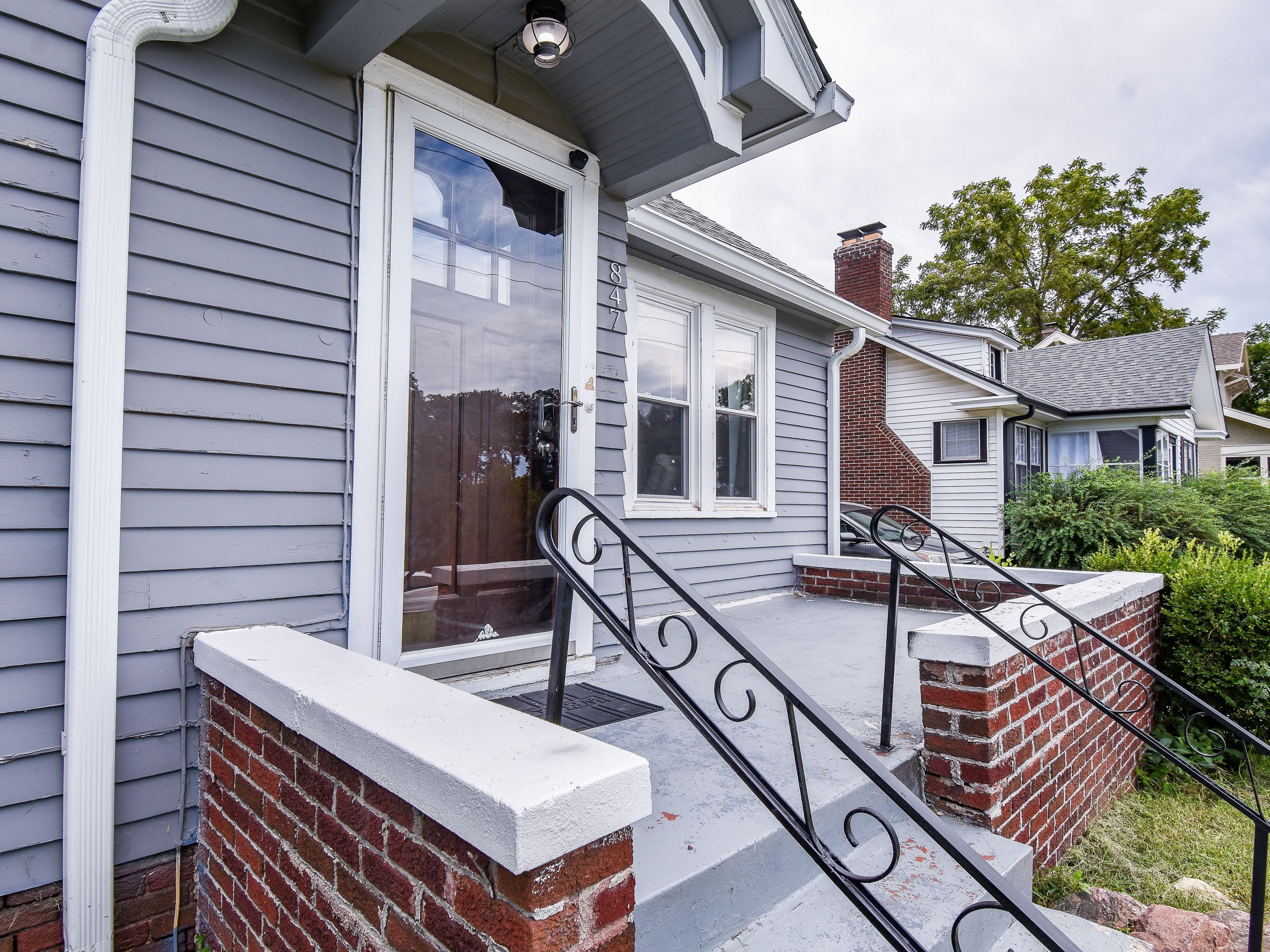 A residential house with a front porch, a brick chimney, and a visible number '847' on the door.