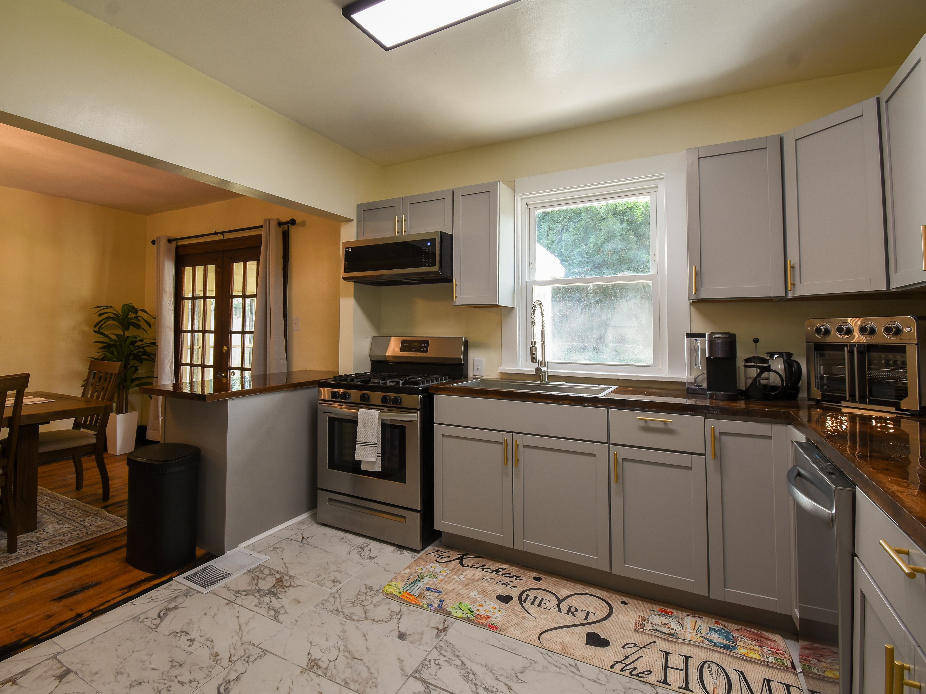 A kitchen with a stove, oven, microwave, and a window.
