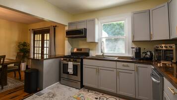 A kitchen with a stove, oven, microwave, and a window.