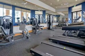 Ein Fitnessstudio mit Cardiogeräten, Gewichtstrainern und einer Spiegelwand.