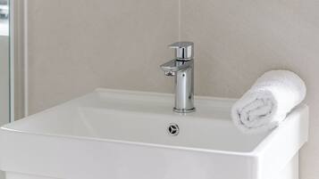Une salle de bain avec un lavabo blanc, un miroir et une serviette.