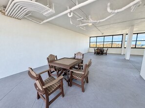 A spacious room with a large table and chairs, white walls, and a view through large windows. - Orange Beach Condo w/ Indoor & Outdoor Pools (Orange Beach)