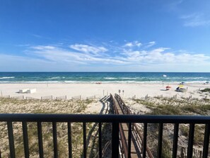 A beach view with a wooden boardwalk leading to the shore, sandy beach, and ocean. - Orange Beach Condo w/ Indoor & Outdoor Pools (Orange Beach)